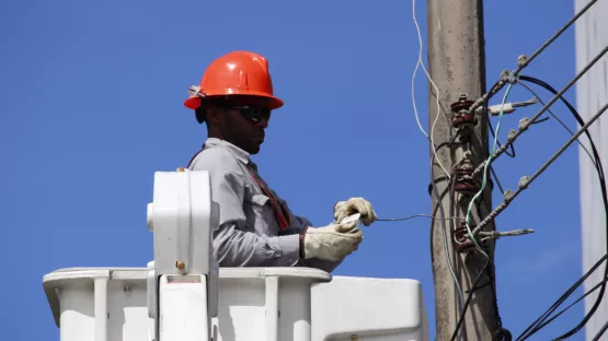 Colaborador de Ibux con casco naranja elevado sobre una grúa hasta los cables de un poste